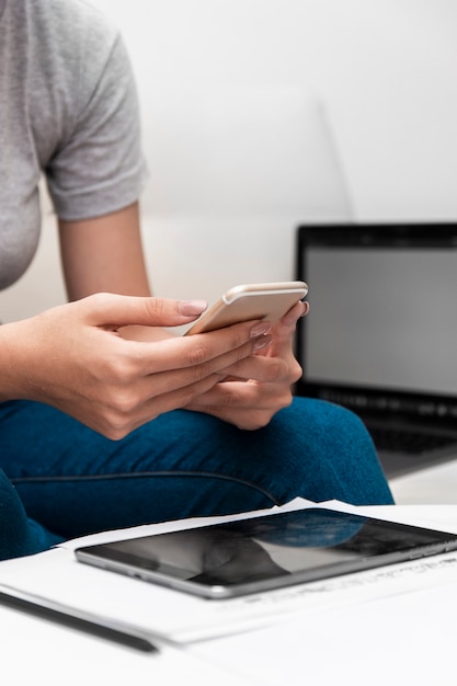 Side view of woman holding smartphone while working at home