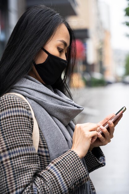 Foto gratuita donna di vista laterale che tiene smartphone