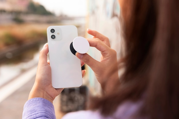 Foto gratuita smartphone della tenuta della donna di vista laterale