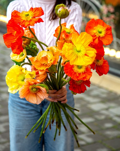 黄色と赤のアネモネの花の花束jpgを保持している女性の側面図