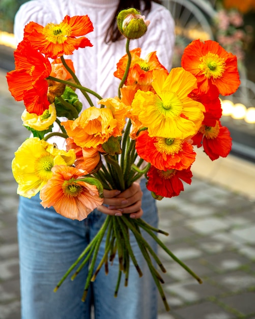 Side view of a woman holding yellow and red anemone flowers bouquet jpg