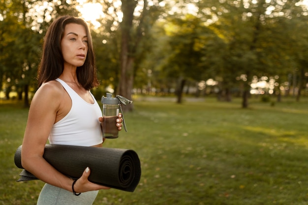 Side view woman holding yoga mat