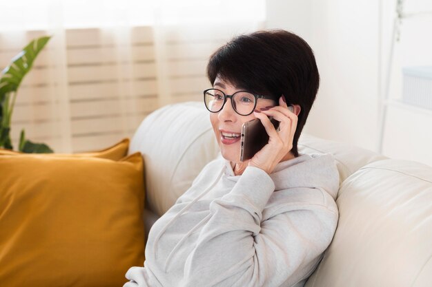 Side view of woman at home talking on smartphone