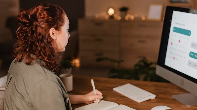 Free photo side view of woman at home using her computer