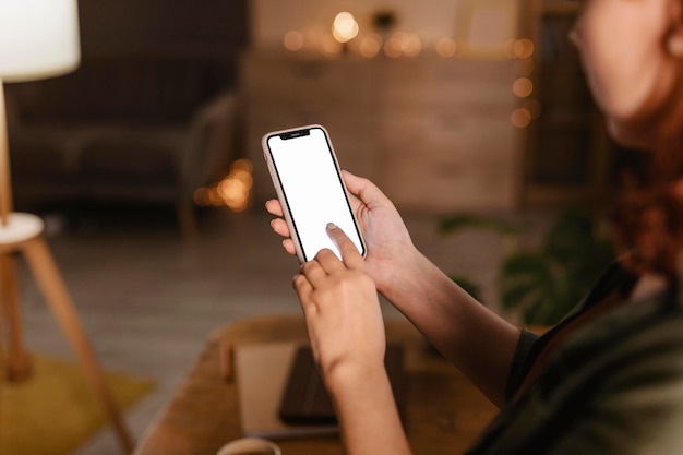 Free photo side view of woman at home using her smartphone