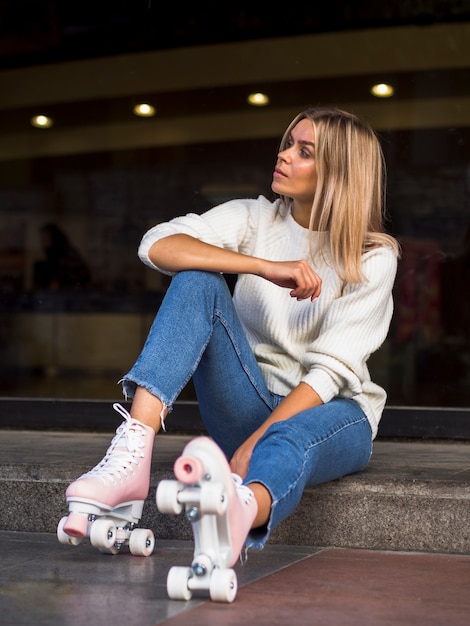 Side view of woman in jeans posing with roller skates