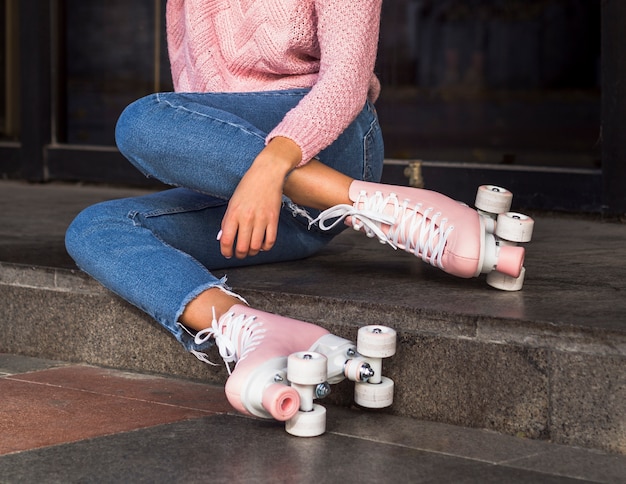 Vista laterale della donna in jeans sulle scale con pattini a rotelle