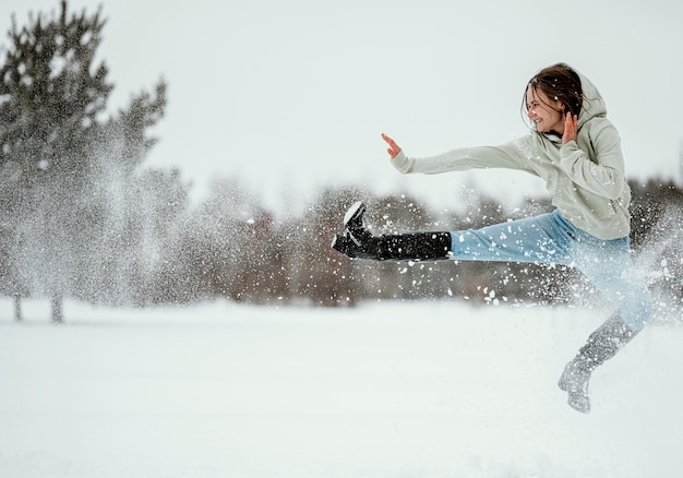 Вид сбоку женщины прыгает на открытом воздухе зимой