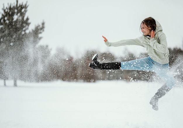 Side view of woman jumping outdoors in winter