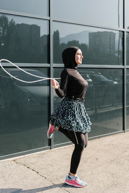 Free photo side view of woman jumping rope