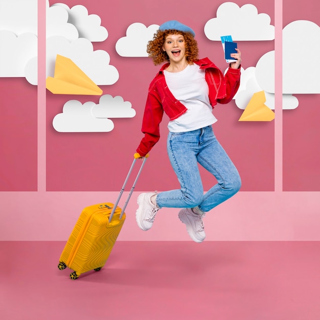 Side view of woman jumping while holding a suitcase and an airplane ticket