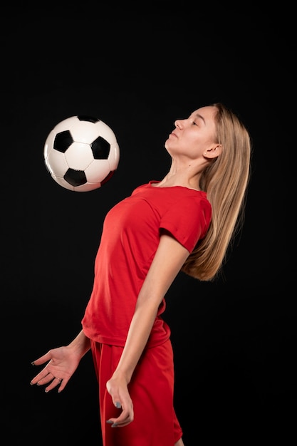胸でサッカーボールを蹴る側面図の女性