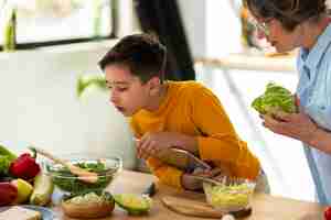 Free photo side view woman and kid cooking together