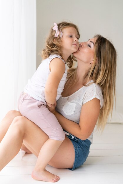 Вид сбоку женщина целует дочь в щеку
