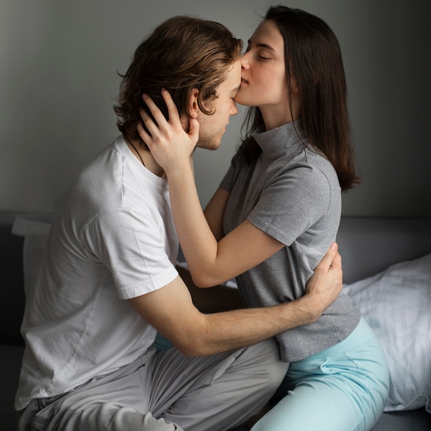 Side view of woman kissing man's forehead