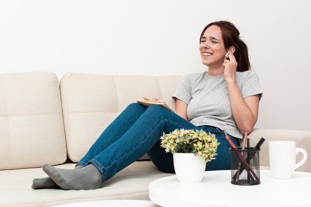 Side view of woman laughing while listening to earphones