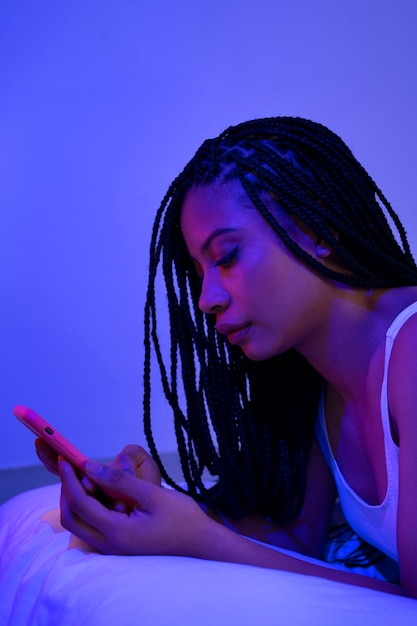 スマートフォンで横たわっている側面図の女性