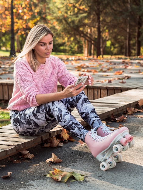 Free photo side view of woman in leggings and roller skates taking selfie