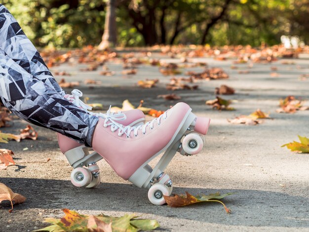Side view of woman in leggings with roller skates and leaves