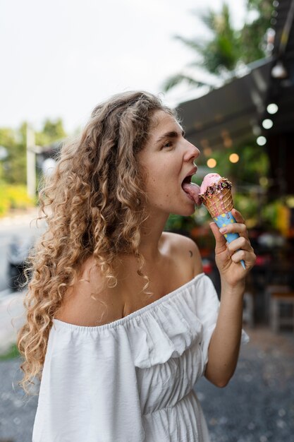 アイスクリームコーンをなめる側面図の女性