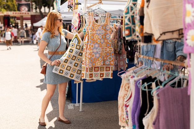 Foto gratuita donna di vista laterale che esamina i vestiti