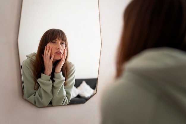 Free photo side view woman looking in the mirror