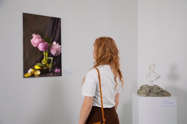 Foto gratuita donna di vista laterale che esamina la pittura