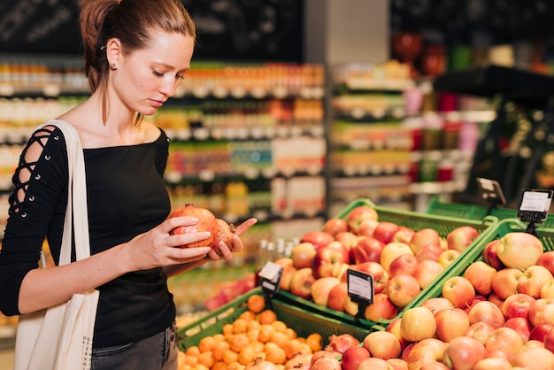 Free photo side view woman looking at pomegranates