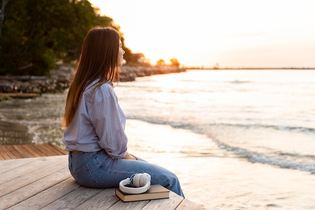 Free photo side view woman looking at the sea at sunset