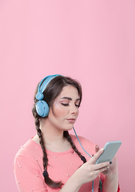 Side view of woman looking at smartphone while wearing headphones