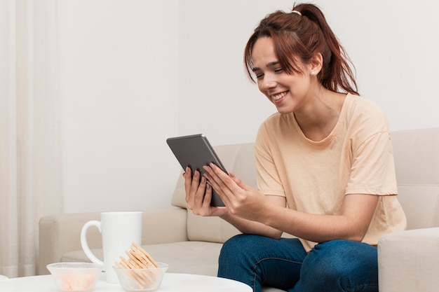 Free photo side view of woman looking at tablet and smiling