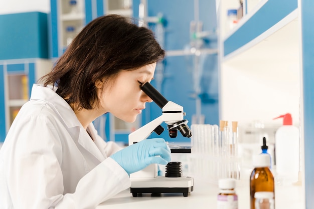 Side view woman looking through a microscope