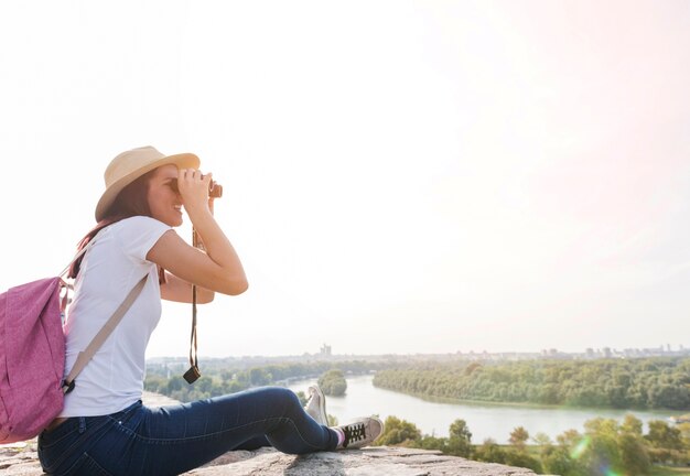Side view of a woman looking at view through binoculars