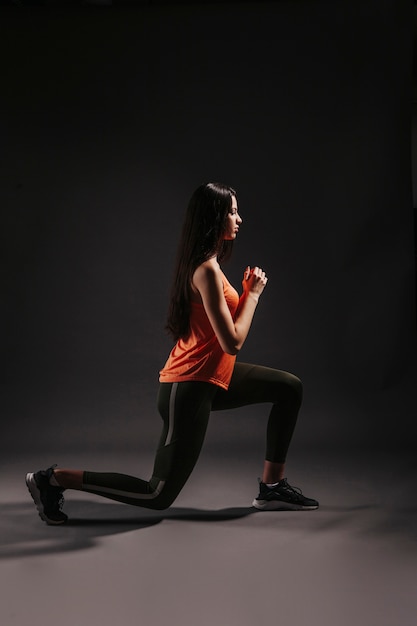 Side view woman lunging in dark studio