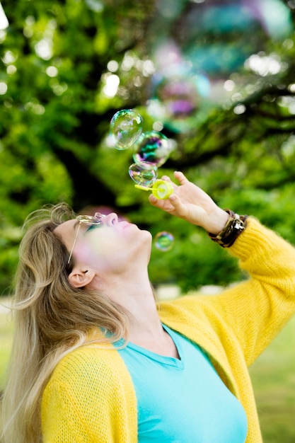 Free photo side view woman making bubbles