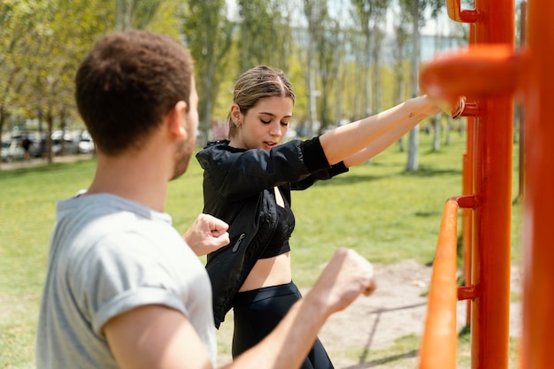 Side view of woman and man exercising together outdoors