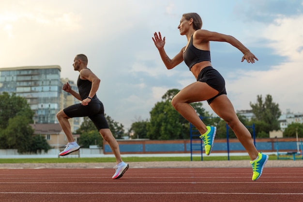 Free photo side view woman and man running on track