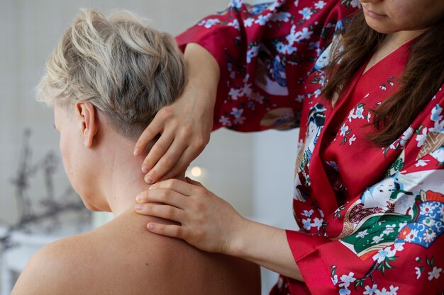 Side view woman massaging client's back