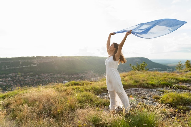 Side view of woman in nature with scarf in the wind