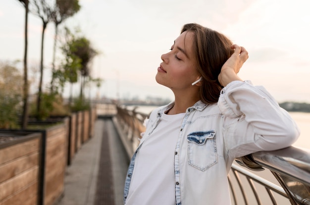 Side view of woman outdoors enjoying music on ear buds