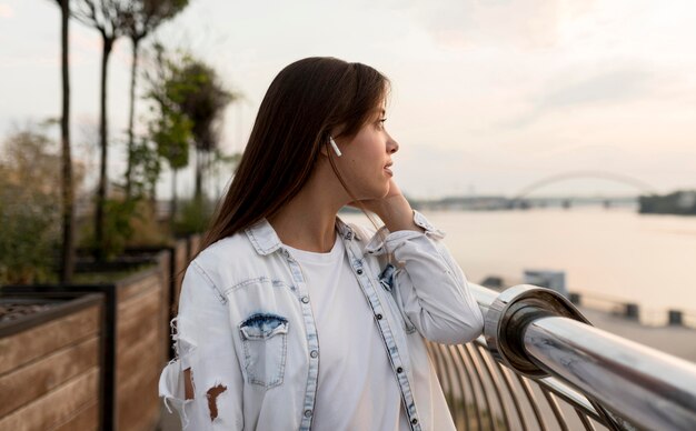 屋外でイヤホンで音楽を楽しむ女性の側面図