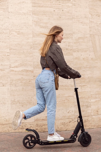 Free photo side view of woman outdoors riding electric scooter