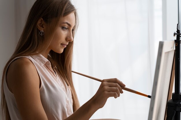 Free photo side view woman painting at home