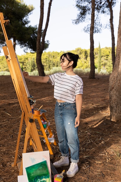 Side view of woman painting outdoors on canvas