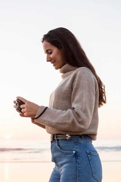 Free photo side view of woman photographing nature with camera