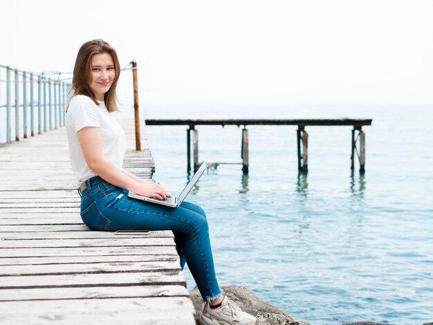 Side view of woman on pier working on laptop