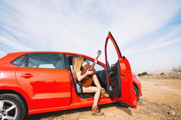 Side view woman playing guitar in car