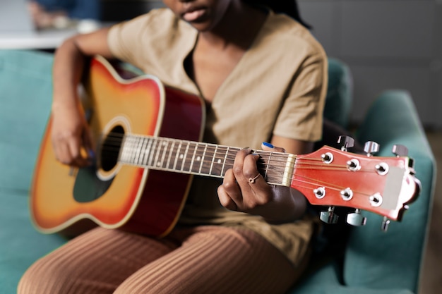 Free photo side view woman playing the guitar