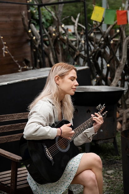 Free photo side view woman playing the guitar