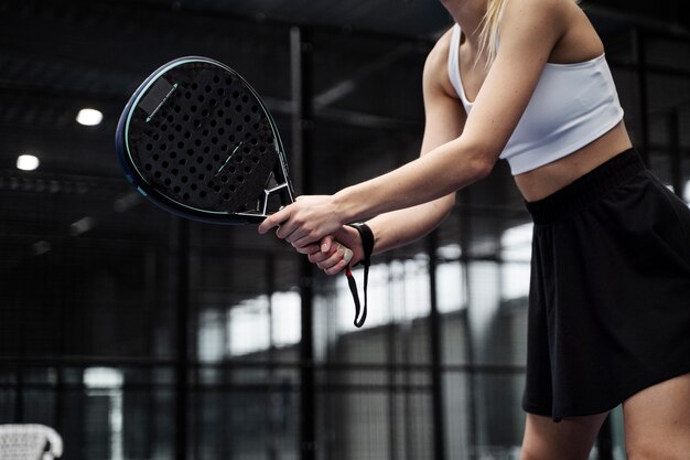 Женщина, вид сбоку, играет в паддл-теннис